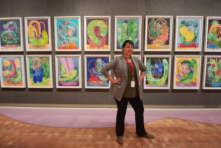 Alumni Duffee Maddox posing in front of a gallery of hanging artwork